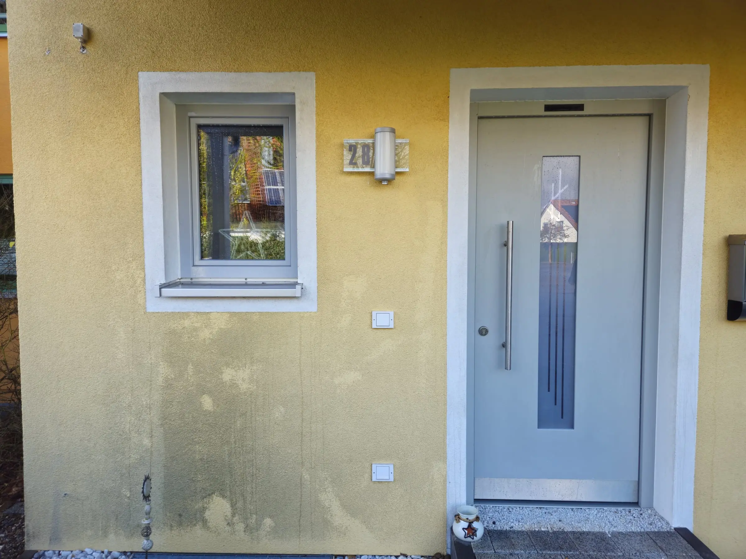 Gelbe Fassade am Hauseingang vor der Reinigung mit dunklen Verfärbungen