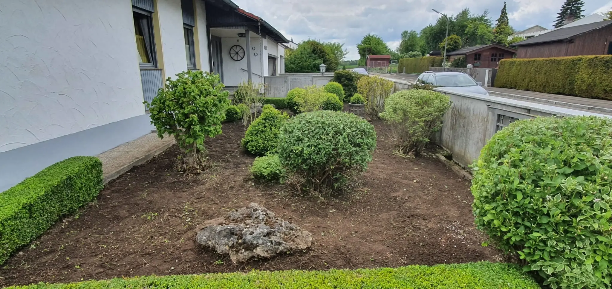 Vorgarten nach dem Ausräumen: offene Erde zwischen den Sträuchern