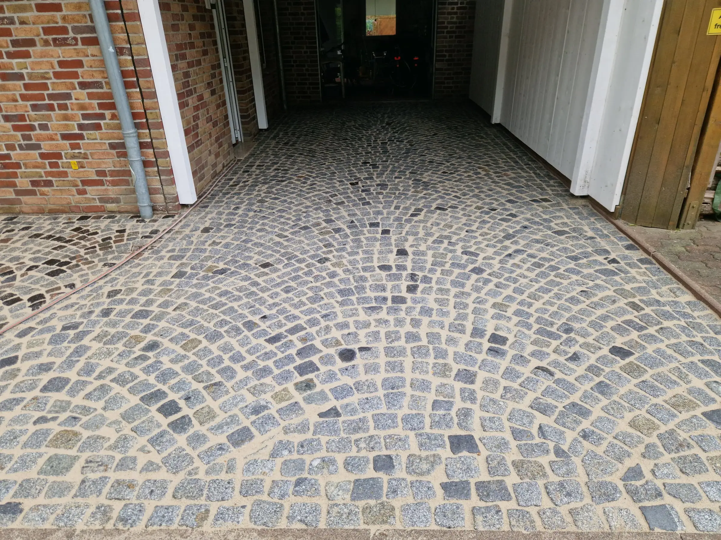 Gereinigtes Granitpflaster im Segmentbogen vor einer Garage